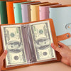 A leather cash organizer ledger is shown open, displaying a $100 bill and surrounded by colorful envelope sleeves.
