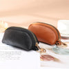 A black leather key organizer wallet with a gold zipper closure resting on a white surface.