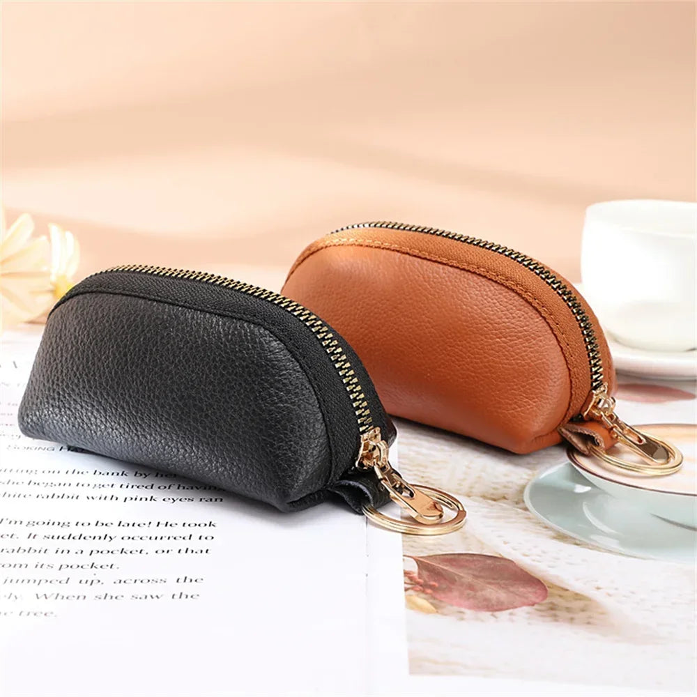 A black leather key organizer wallet with a gold zipper closure resting on a white surface.