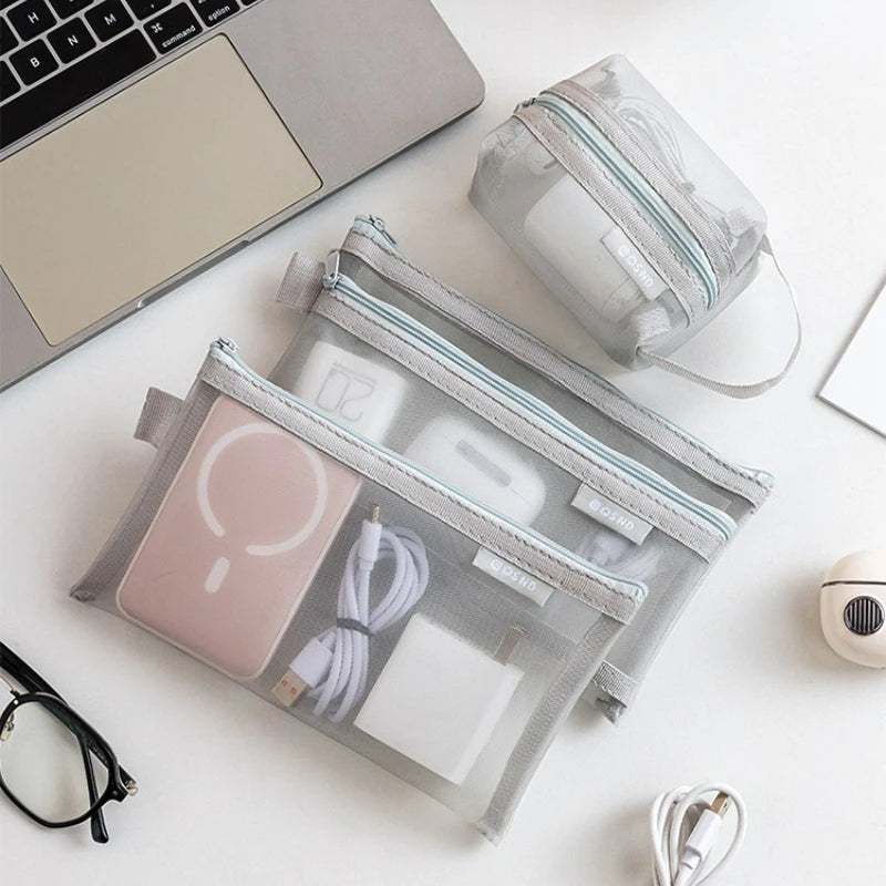A set of six transparent mesh storage bags is displayed next to a laptop and a small zippered pouch on a white surface.