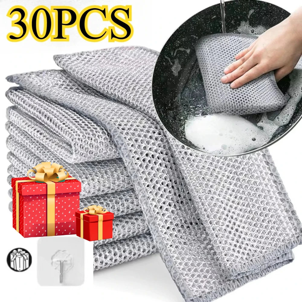 A stack of 30 pieces of gray metal wire cleaning cloths, with one cloth being used to clean a black pan.
