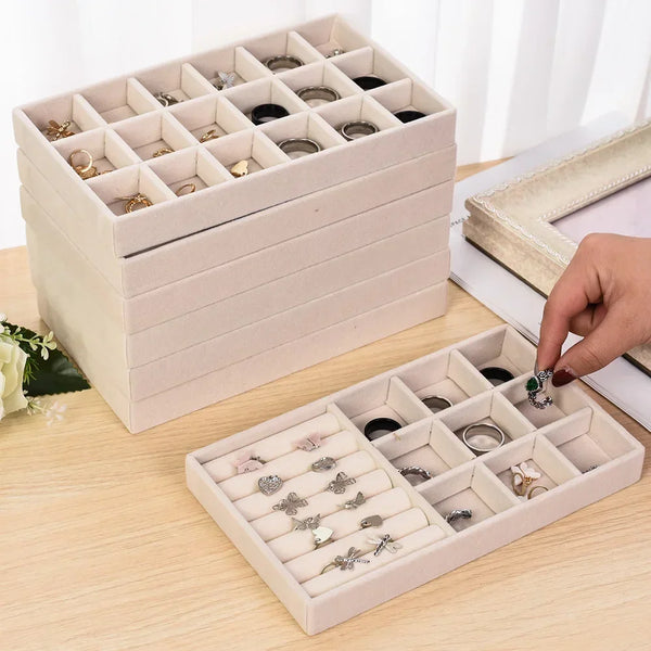 A light beige velvet jewelry organizer tray with soft lining displaying various rings and jewelry.