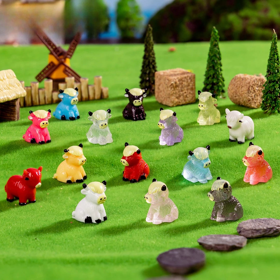 A collection of resin highland cow figurines in various colors and sizes displayed on green felt.