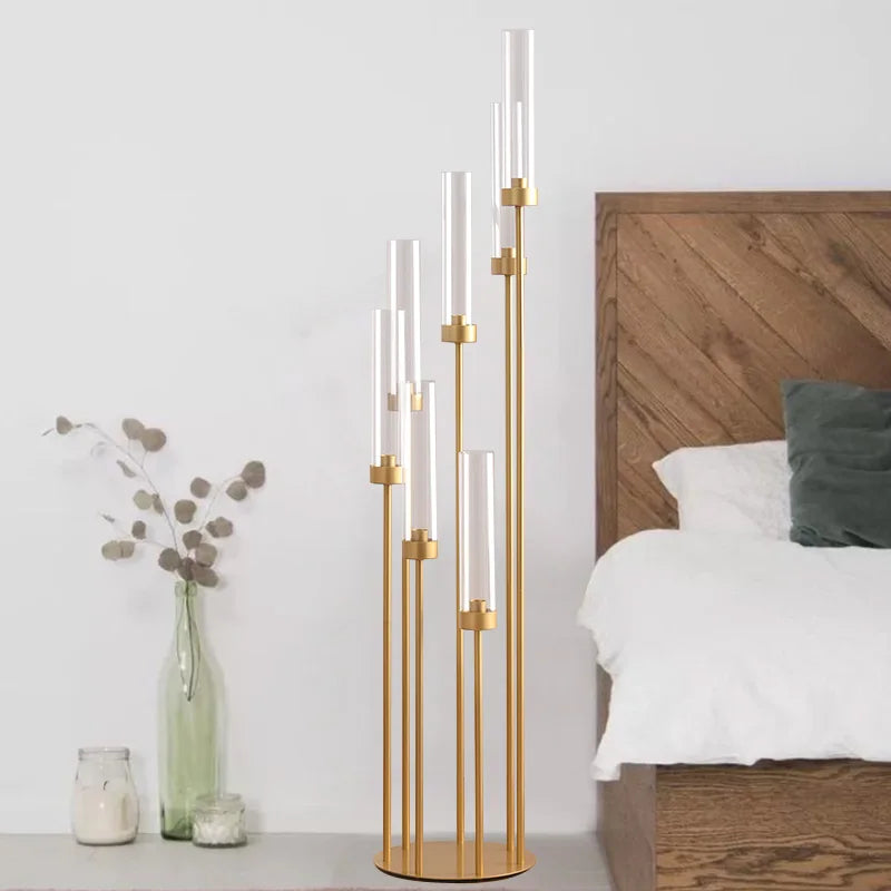 Un juego de candelabros de oro con siete brazos de vidrio esbelto, exhibido junto a un marco de cama de madera.