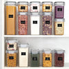 A collection of five clear plastic food storage containers filled with various dry goods like spaghetti, cookies, peanuts, fl
