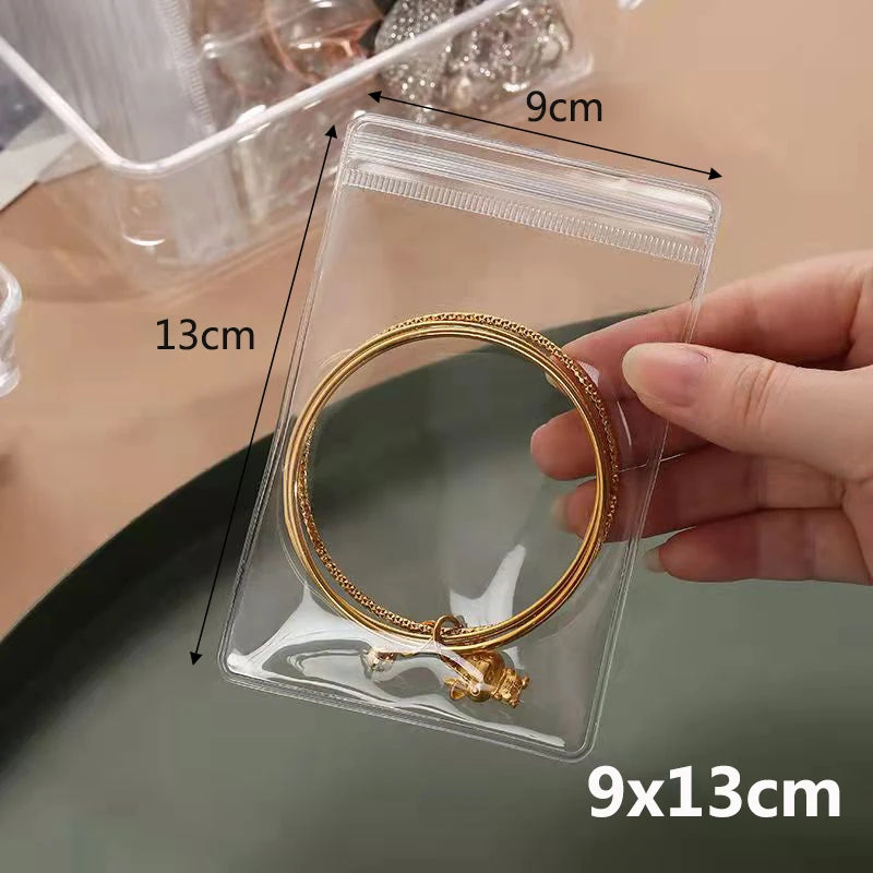 A clear plastic zip lock pouch holds a gold-colored ring with a small charm.