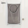 Two gray fabric laundry organizers with circular openings hanging on a white door.