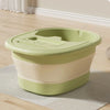 A light green portable foldable foot bath tub with beige stripes resting on a light rug.