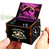 An antique wooden hand crank music box featuring a Jurassic Park themed box art with a dinosaur silhouette.