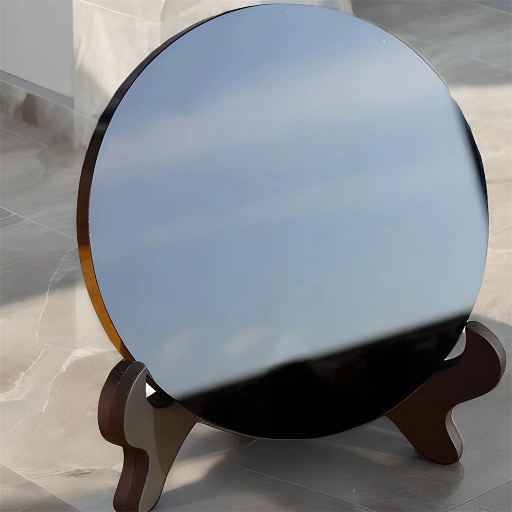 A round black obsidian scrying mirror decor resting on a wooden stand.