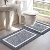 A white toilet and sink area with two gray microfiber non-slip bath mats on the floor.