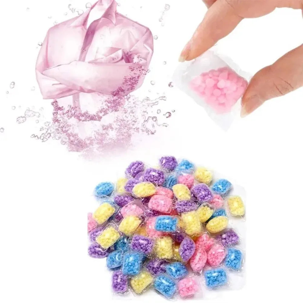 A hand is squeezing pink laundry fragrance beads, with loose pink and multi-colored beads scattered below.