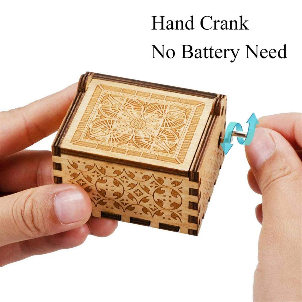 A hand is holding a vintage engraved wooden music box with a hand crank for operation.