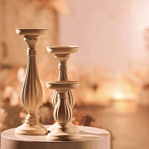 A pair of antique wood decorative candlestick holders with fluted stems and round tops displayed on a white surface.