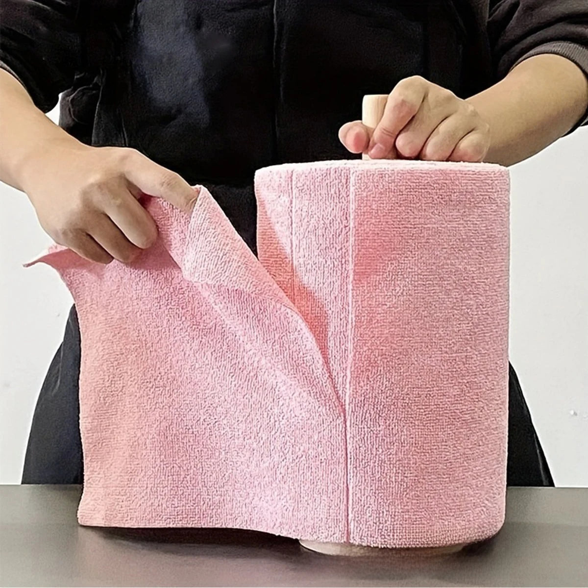 A pink reusable multi-surface cleaning wipe is being held by a person.