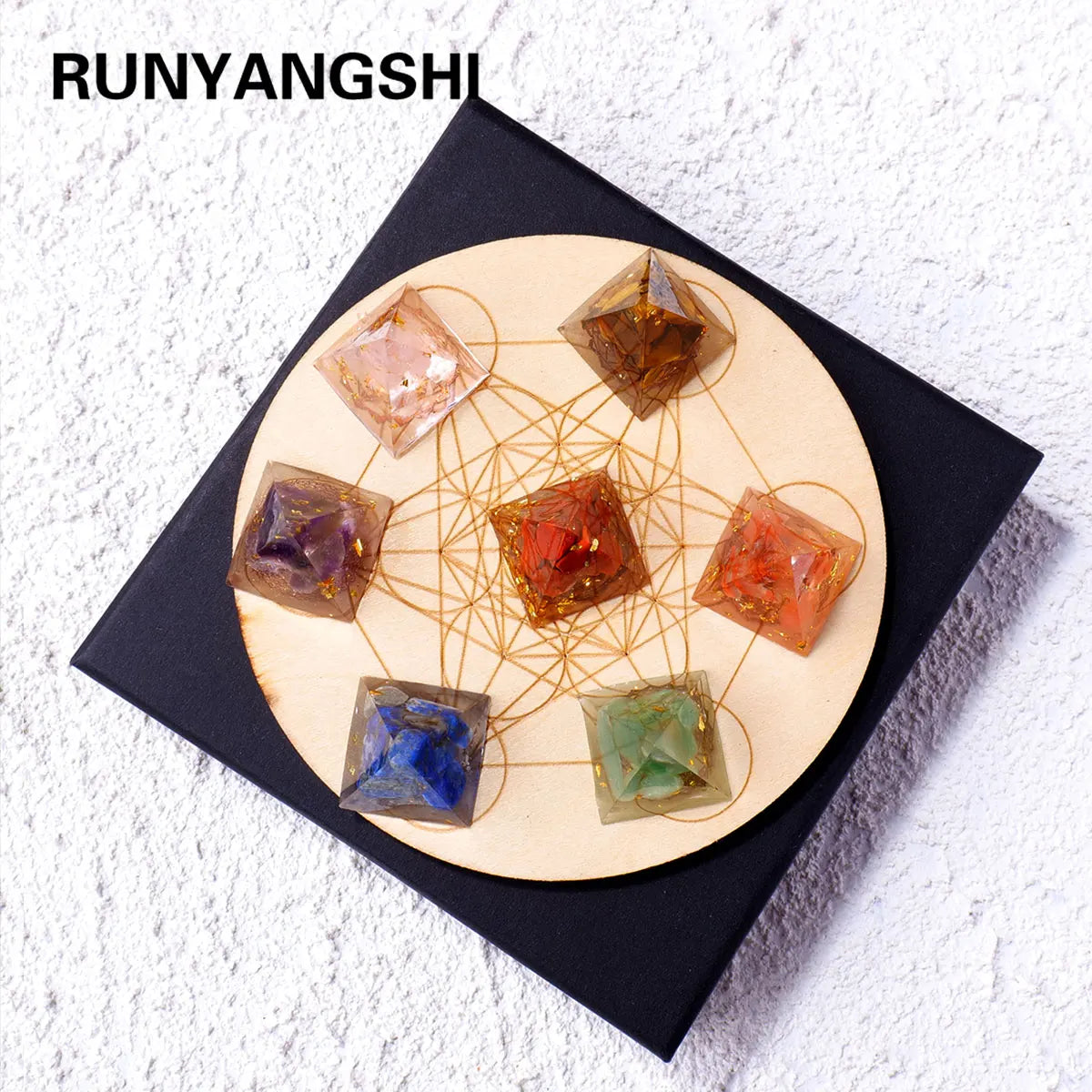 A set of natural stone chakra pyramids arranged on a wooden circle with thin golden lines.
