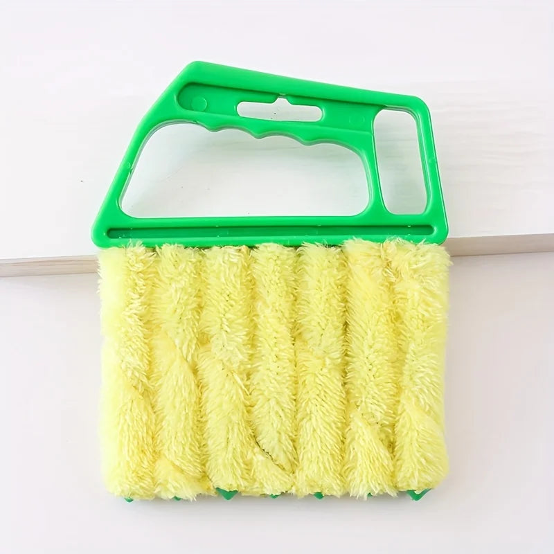 A yellow bristled brush with a green handle used for cleaning window blinds.