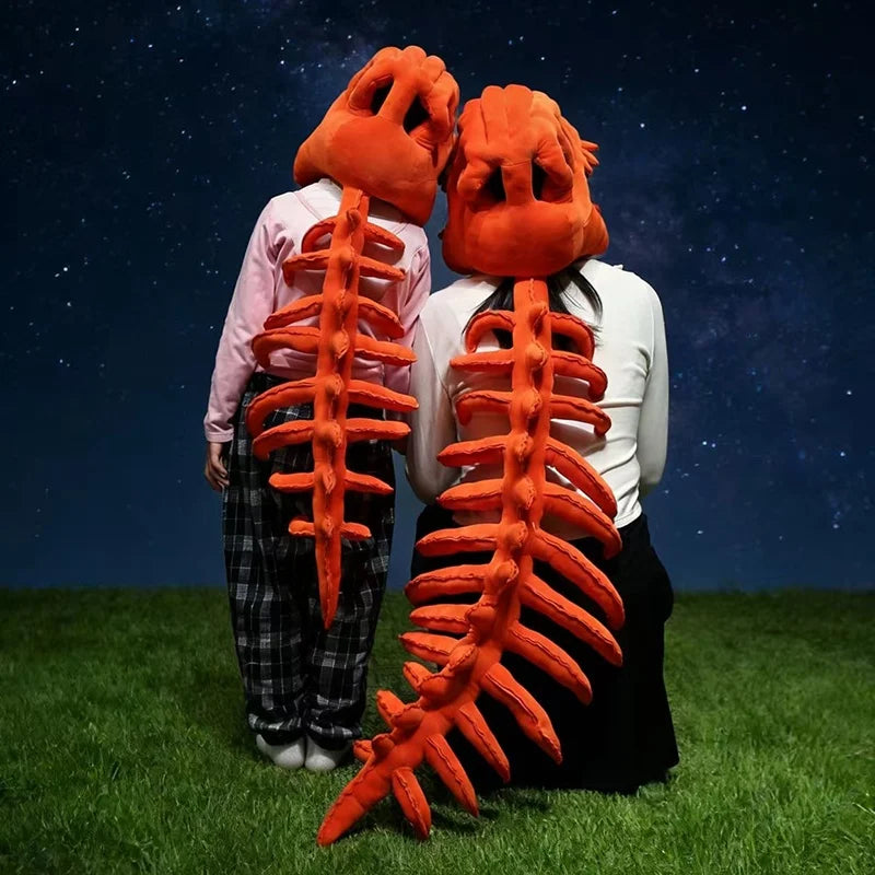 A person wearing a realistic dinosaur skeleton costume, featuring an orange skull and rib cage, standing in a grassy field un