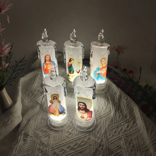 A set of four clear glass votive candles with figures inside, displayed on a white textured cloth.