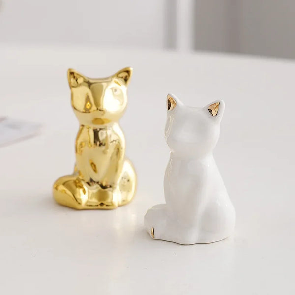 A pair of ceramic elephant rabbit jewelry racks, one gold and one white, sitting on a white surface.
