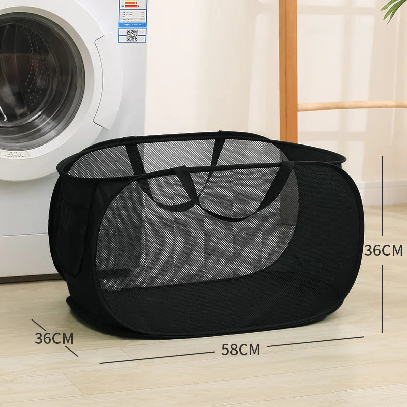 Black foldable mesh laundry basket with handles shown on a wooden floor.