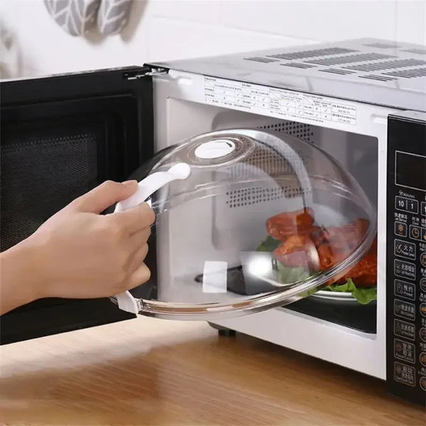 A hand is removing a transparent splash-proof oven cover with a handle from an open microwave oven.