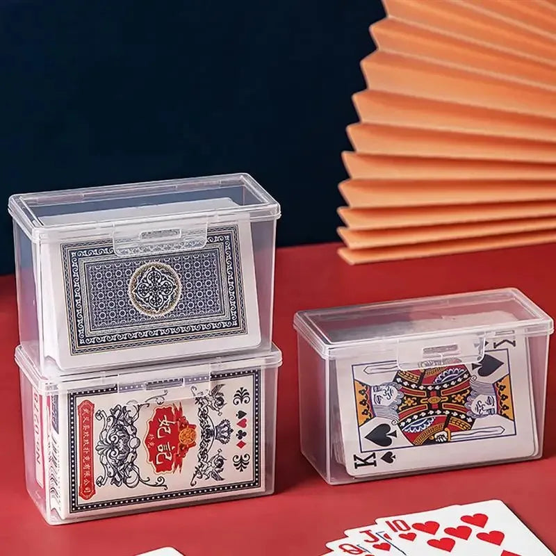 A set of transparent plastic storage boxes for cards and sundries resting on a red surface.