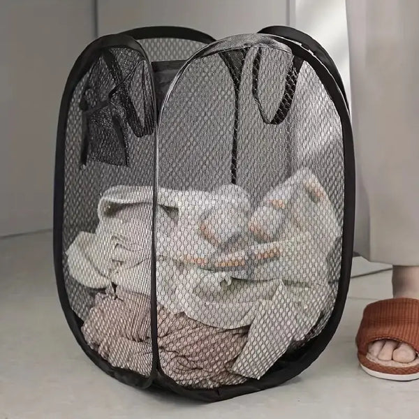 A black mesh pop-up laundry basket filled with white and beige clothing.