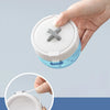 A hand is holding a clear plastic container with a white lid and a gray cross-shaped opening, demonstrating the portable mult