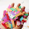 A hand holds a colorful confetti decoration set consisting of various colored paper pieces.
