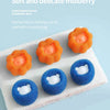 Several soft and delicate mulberry cleaning balls in orange, blue, and yellow are displayed on a white towel.