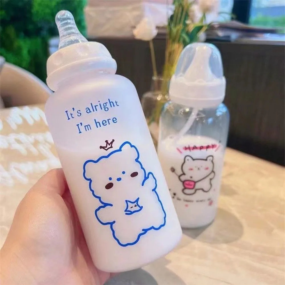 A clear plastic bottle of strawberry bear shaped liquid is shown next to a glass bottle with a cat design.