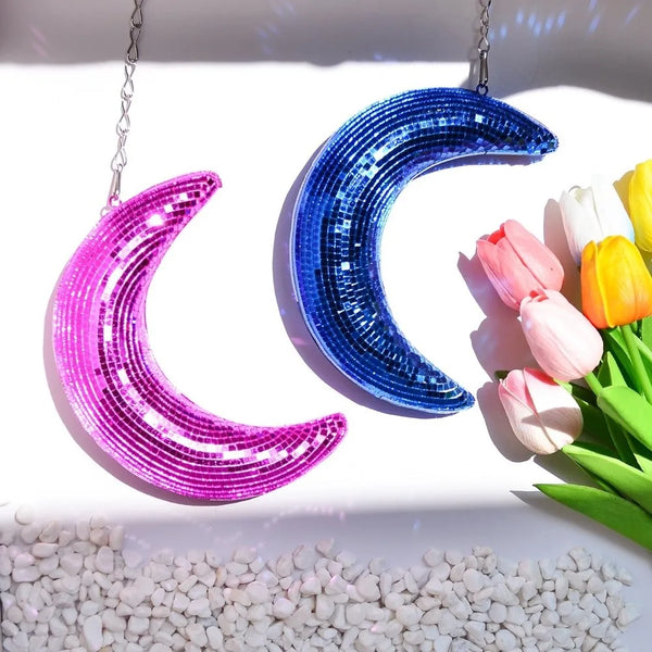 Two crescent moon pendants made of iridescent purple and blue sequins displayed against a white background with pink and yell
