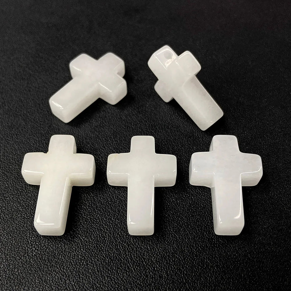 Four white natural agate and jasper cross pendant charms arranged on a dark surface.