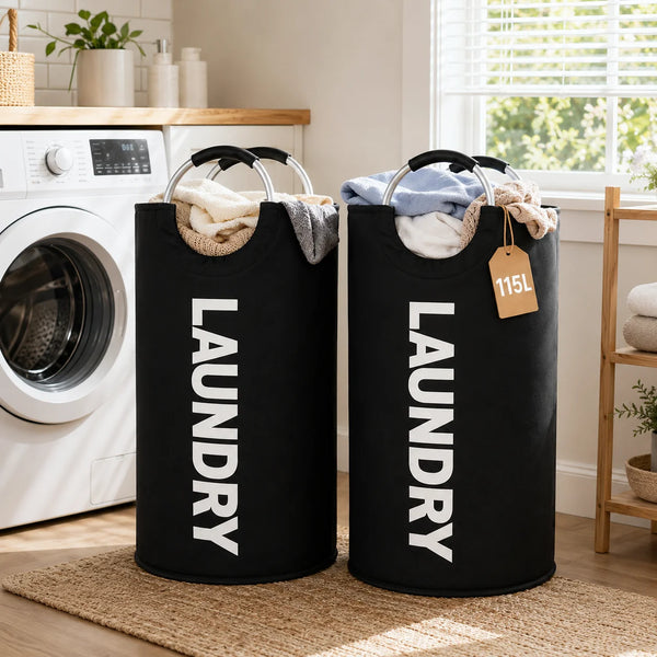 A pair of black fabric laundry hampers with handles are displayed on a woven rug next to a washing machine.