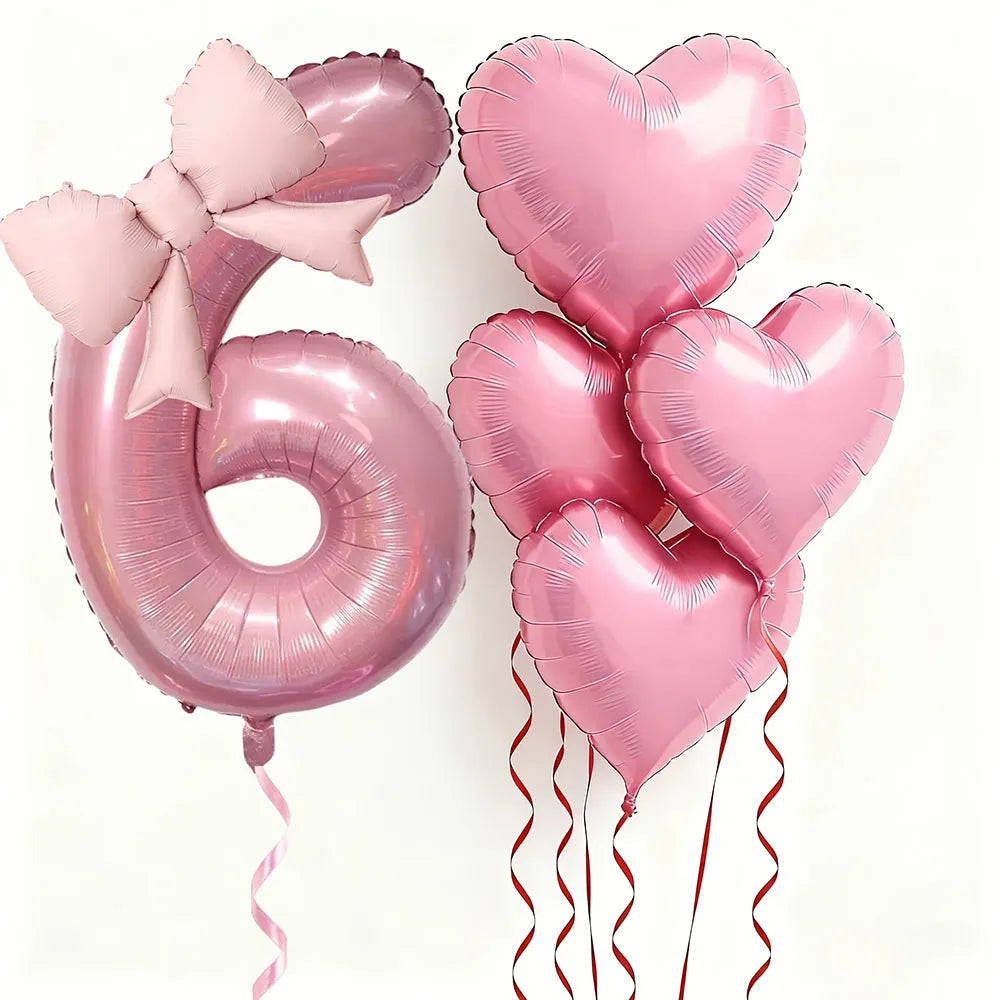 Un set de seis globos de aluminio en forma de corazón rosa que forman el número 6, atados con cintas rosas.