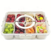 A clear plastic tray with eight compartments filled with various fresh fruits and snacks like tomatoes, olives, and citrus sl