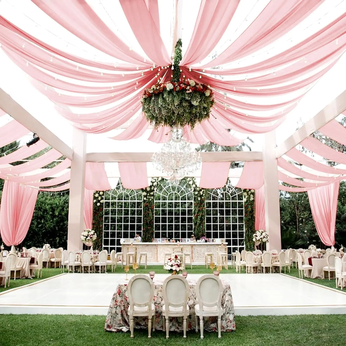 Pink sheer chiffon draping fabric creating a romantic ceiling canopy for an outdoor event.