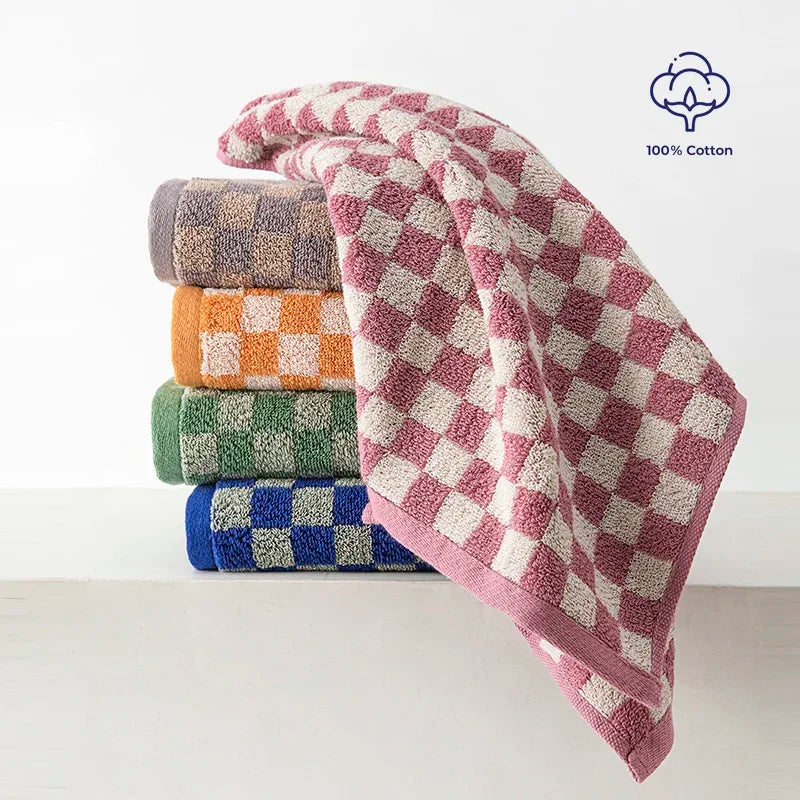 A stack of plaid cotton bath towels in various colors, including pink, purple, blue, and green.