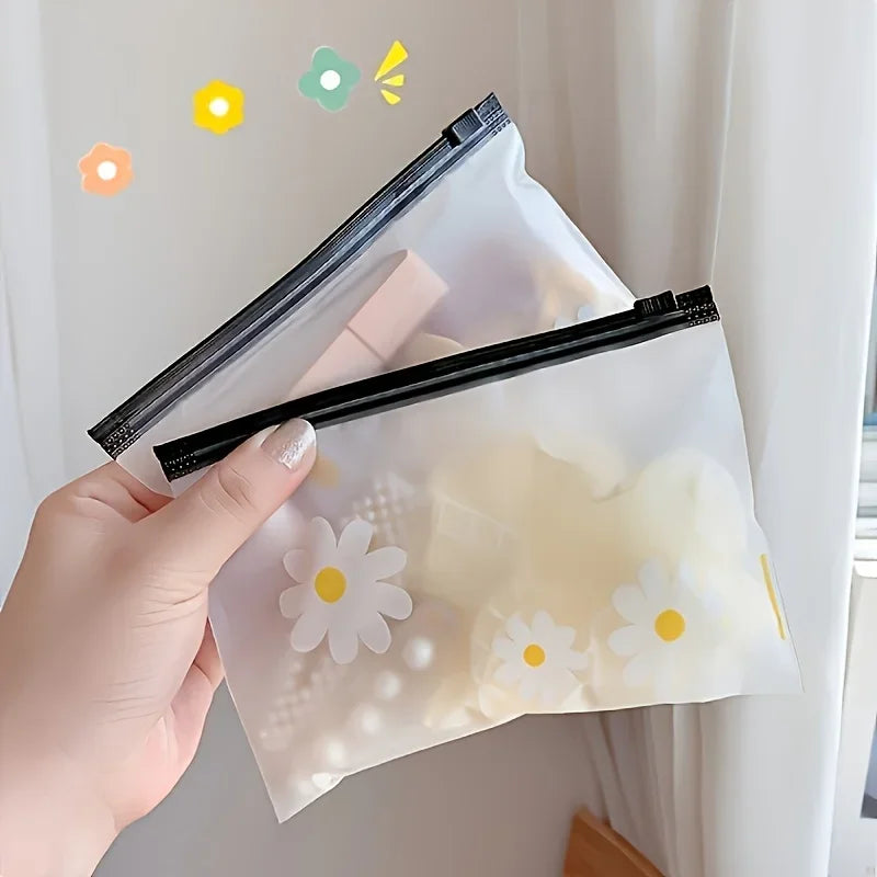 A hand holds a clear plastic zipper storage bag with a white daisy pattern, against a light background.