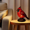 A decorative resin bird sculpture resembling a cardinal sits on a wooden table.