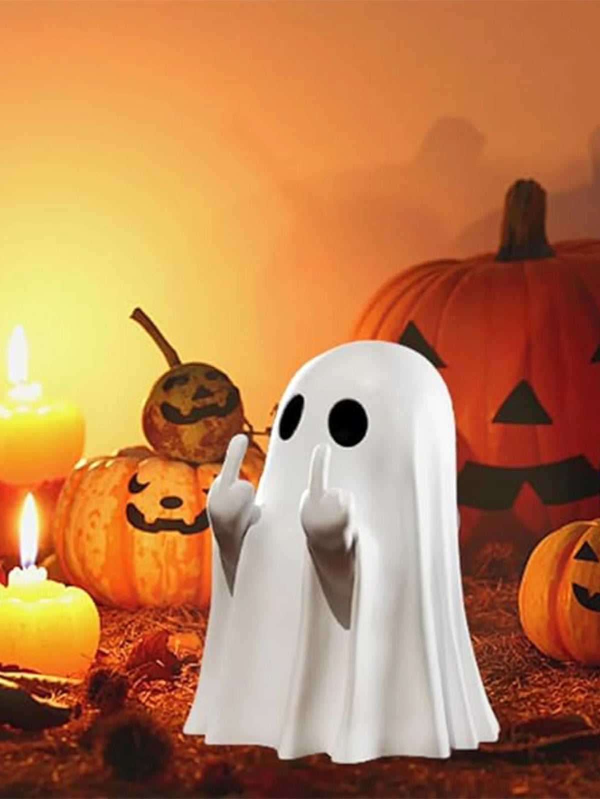 A white ghost statue decoration stands in front of carved pumpkins and a glowing candle on a dark surface.