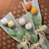 Un bouquet de cœurs de coton faits main, fleurs de carnation orange et jaune, attachés avec un ruban transparent.