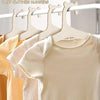 Wooden clothing hangers with horse-shaped hooks displaying light yellow and beige baby clothes.