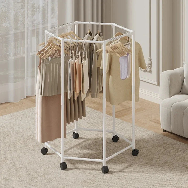 A white rotating hexagon clothes rack with wooden hangers displaying various garments in a bright indoor setting.