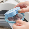 A hand is opening a light blue floating laundry mesh filter bag inside a washing machine drum.