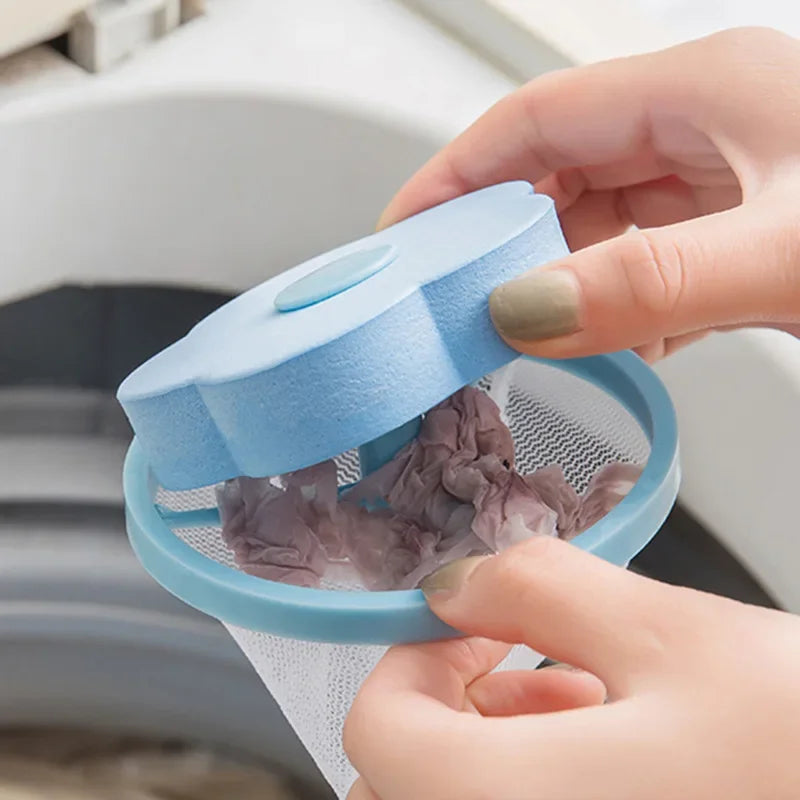 A hand is opening a light blue floating laundry mesh filter bag inside a washing machine drum.