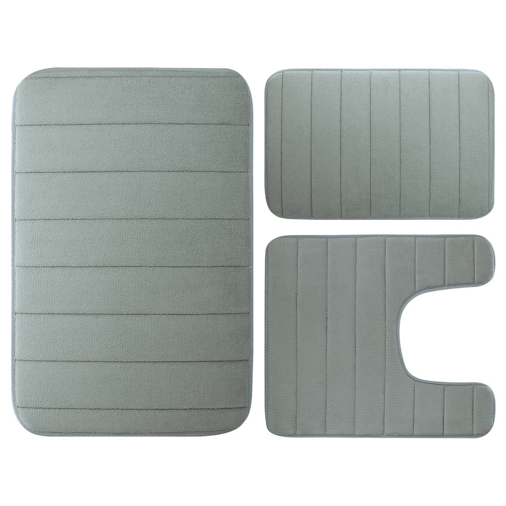 Ein Set aus drei grauen Memory-Foam-Badezimmerteppichen, bestehend aus einer rechteckigen Matte und zwei unregelmäßigen Forme