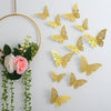 Gold glitter butterfly wall stickers hanging from a gold hoop with green foliage