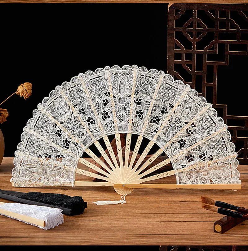 Elegant lace folding handheld fan with a light beige color displayed on a wooden surface.